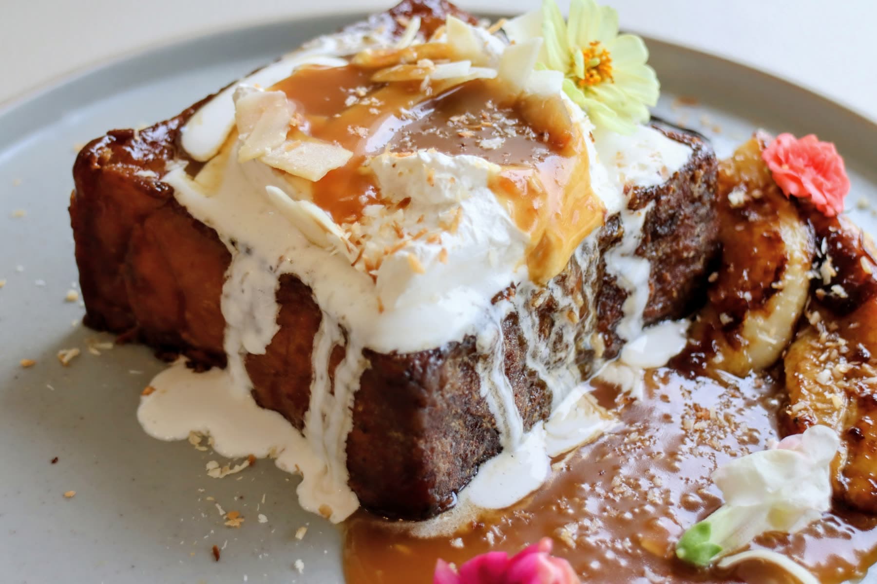 Coconut french toast with cream and caramel, topped with an edible flower